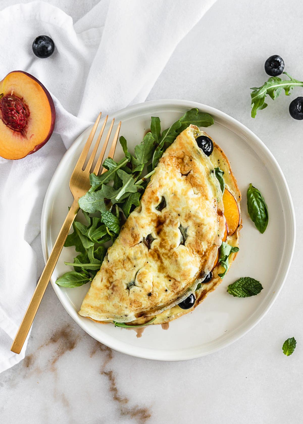 A Peach, Blueberry and Arugula Omelet is an easy, healthy omelet made with summer fruit and spicy arugula for a healthy meal any time of day! (gluten-free, vegetarian) | via livelytable.com