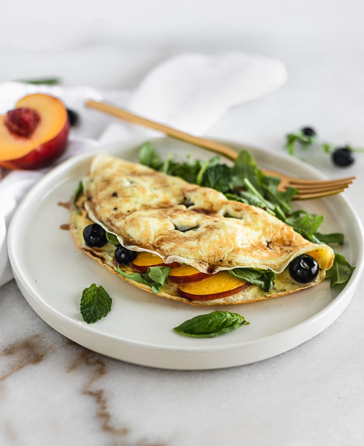 A Peach, Blueberry and Arugula Omelet is an easy, healthy omelet made with summer fruit and spicy arugula for a healthy meal any time of day! (gluten-free, vegetarian) | via livelytable.com