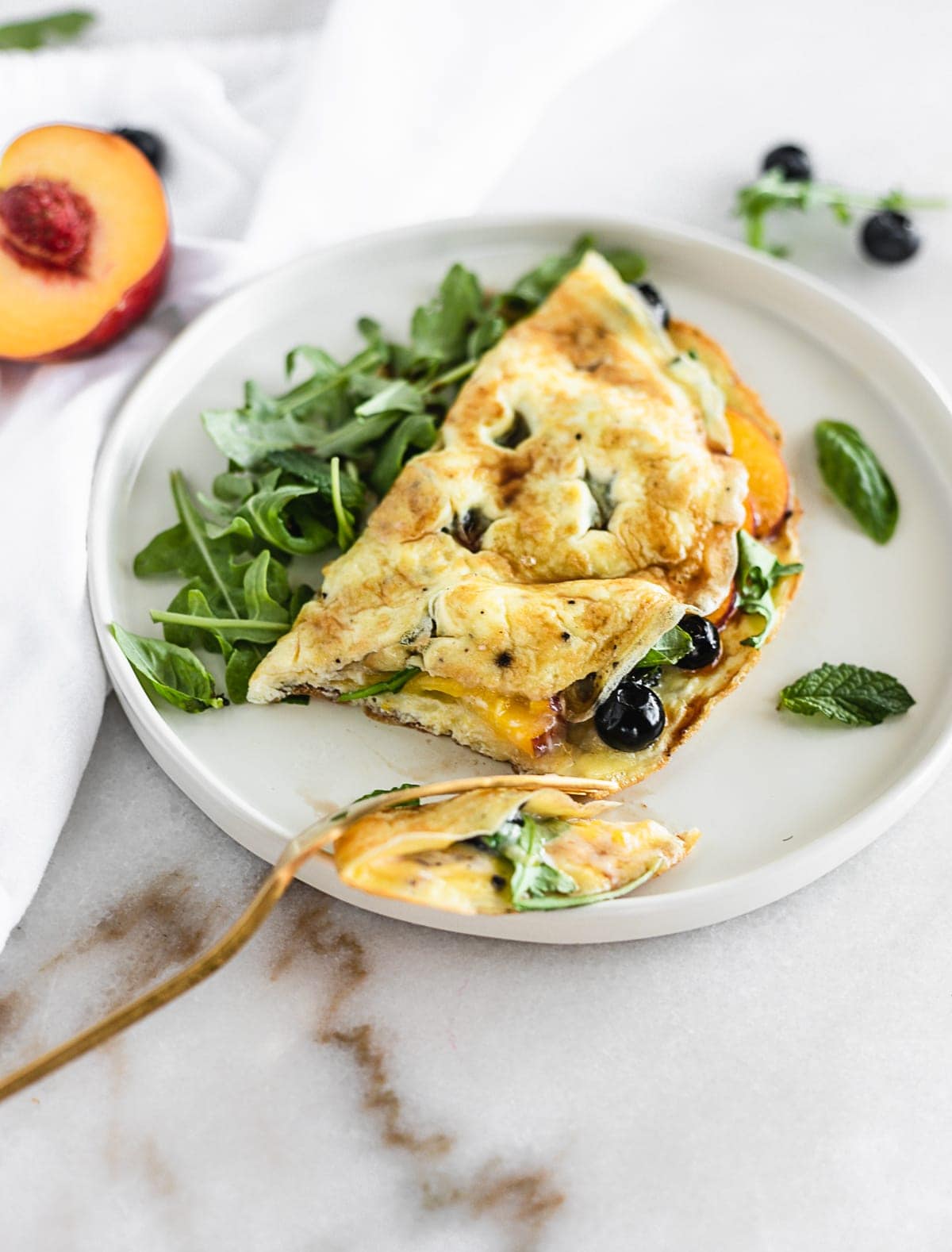 A Peach, Blueberry and Arugula Omelet is an easy, healthy omelet made with summer fruit and spicy arugula for a healthy meal any time of day! (gluten-free, vegetarian) | via livelytable.com