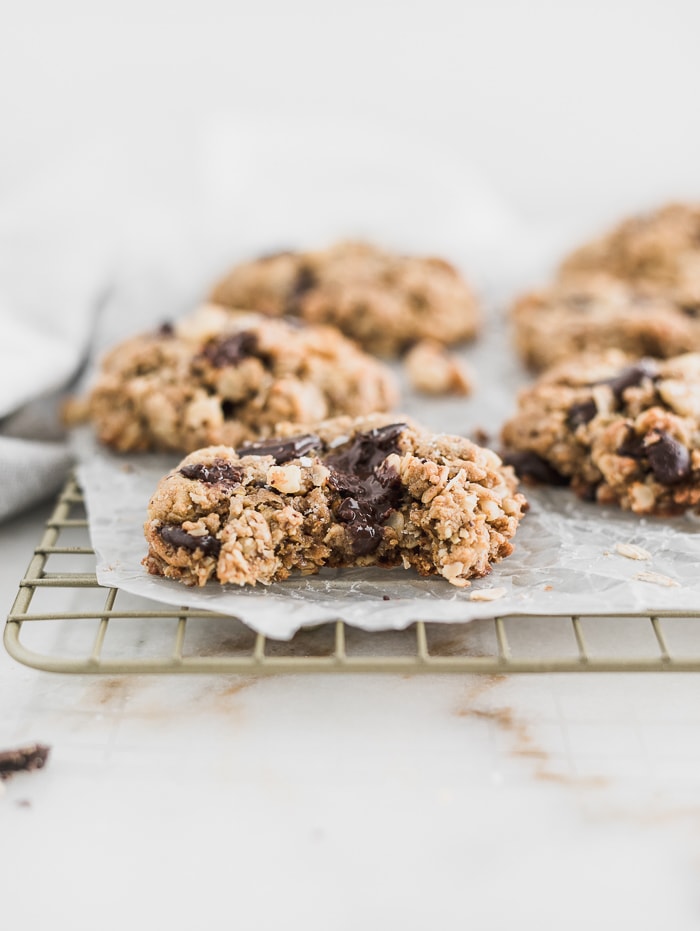 gluten free oatmeal chocolate chunk cookie with a bite taken out on a cooling rack covered in parchment.