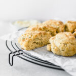 closeup of rosemary parmesan scones on top of a parchment lined black cooling rack.