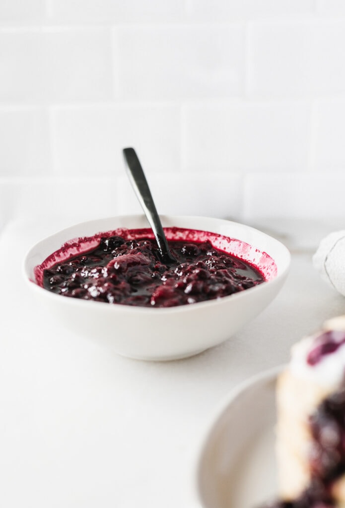 white bowl of easy berry compote with a black spoon in it.