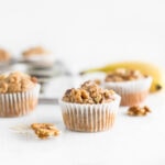 Close up of healthy blender gluten-free banana nut muffin surrounded by walnuts.