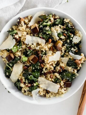 overhead view of roasted eggplant kale quinoa salad in a white bowl.