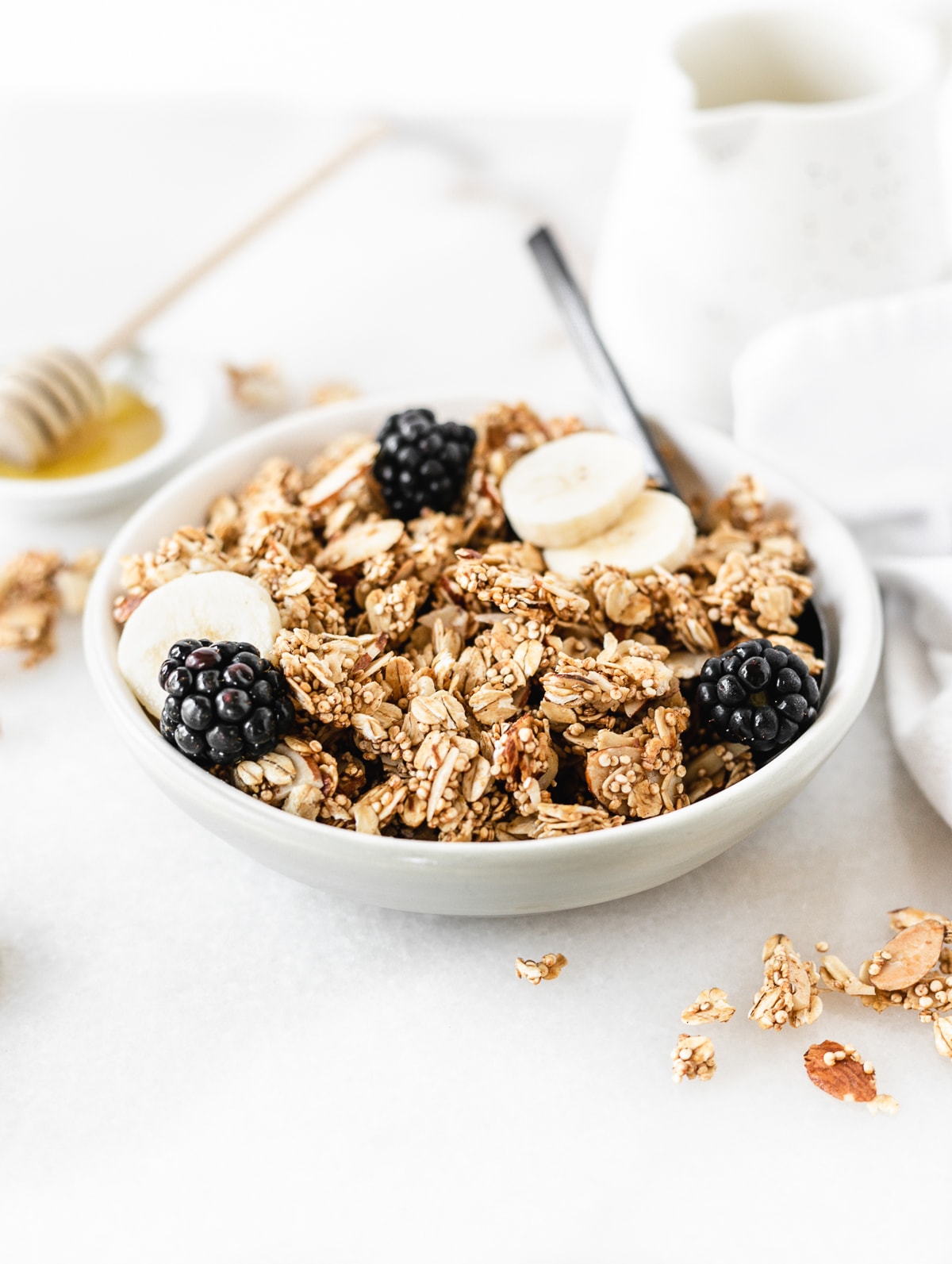 bowl of honey almond quinoa granola topped with blackberries and banana slices.