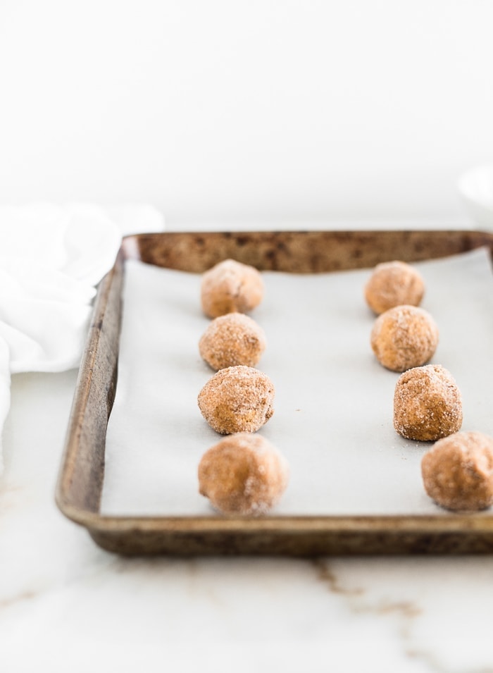 balls of pumpkin snickerdoodle cookie dough on a parchment-lined baking sheet.