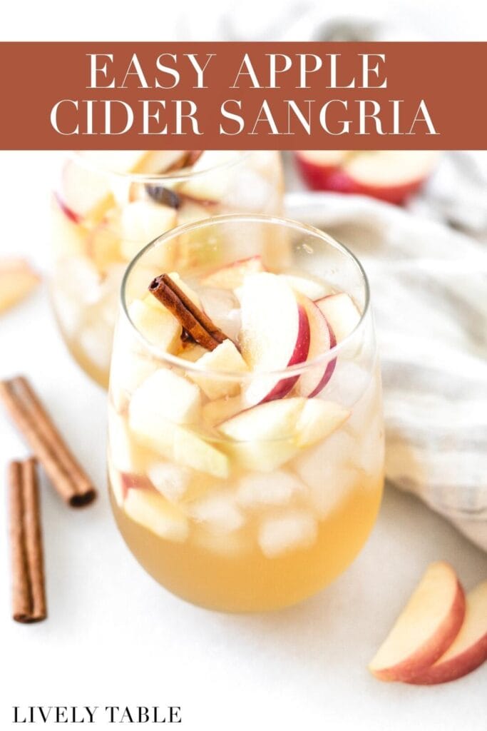 glass of apple cider sangria with apple slices and cinnamon sticks in it with text overlay.