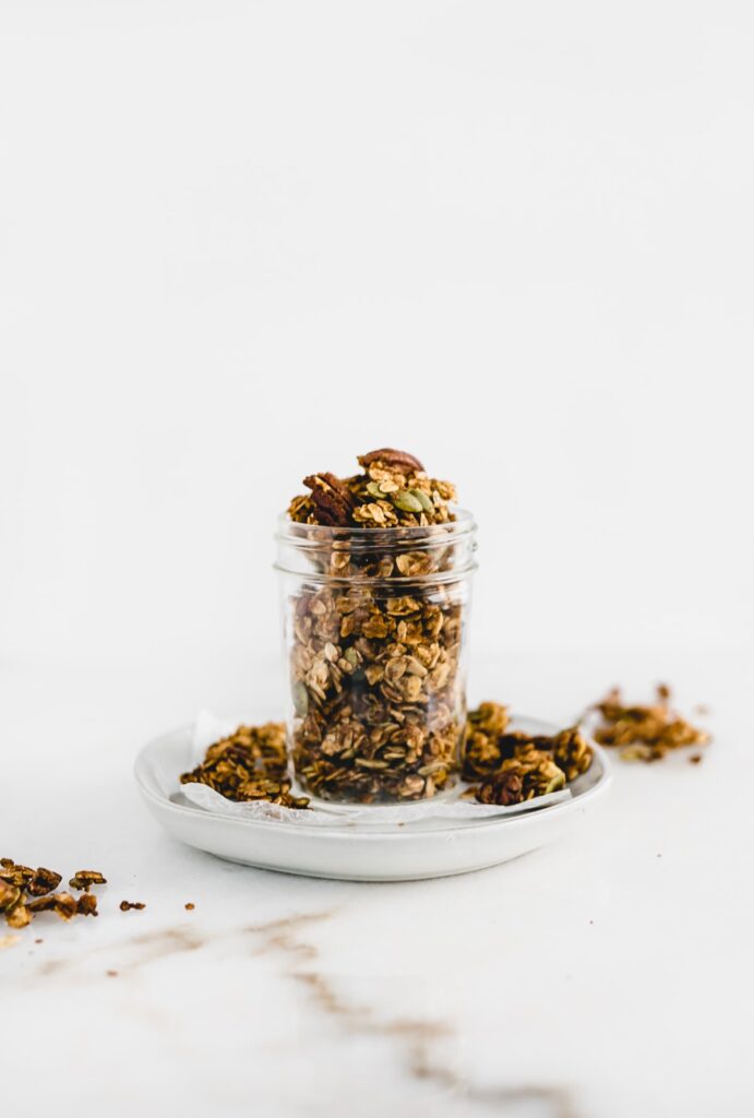 Chunky pumpkin granola in a clear container on a plate.