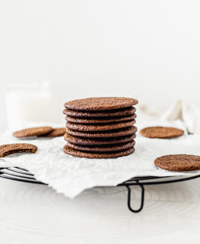 gingersnaps stacked on top of each other on a cooling rack lined with parchment.