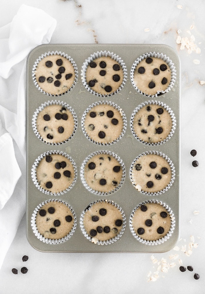 a muffin tin filled with banana chocolate chip muffin batter.