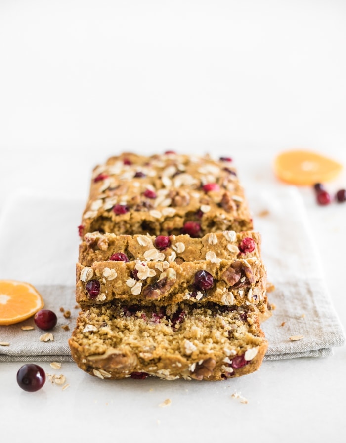 Healthy cranberry orange oatmeal bread with a few slices cut off the loaf on top of a napkin.
