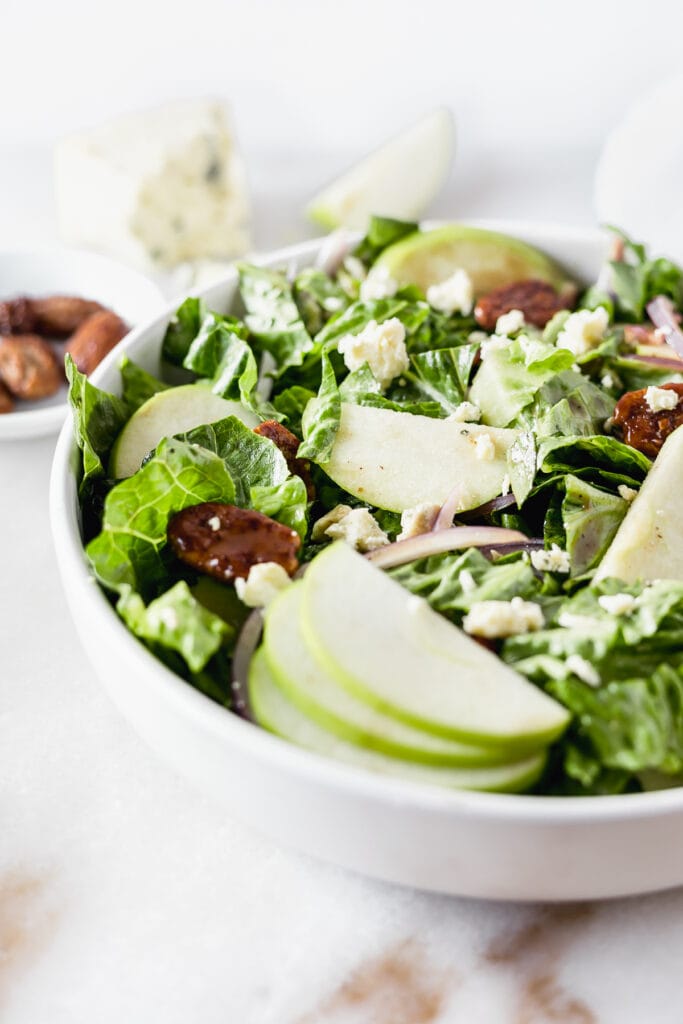 closeup of a romaine salad with granny smith apple slices and blue cheese.