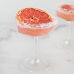 broiled grapefruit paloma in an old fashioned martini glass rimmed with sugar.