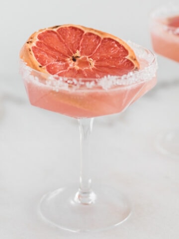 broiled grapefruit paloma in an old fashioned martini glass rimmed with sugar.