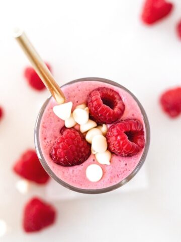 overhead view of raspberry white chocolate smoothie with a gold straw in it.