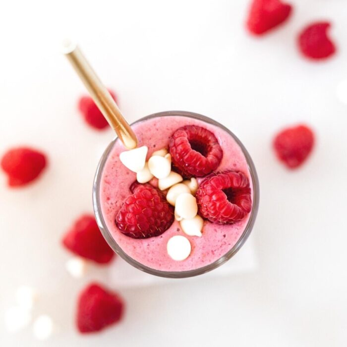 overhead view of raspberry white chocolate smoothie with a gold straw in it.