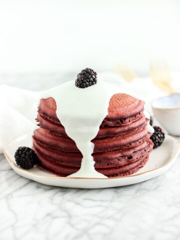 healthy red velvet pancakes with cream cheese glaze and blackberries on top.