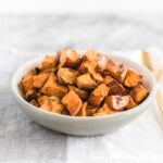 simple roasted sweet potato cubes in a white bowl on top of a folded grey and white napkin.