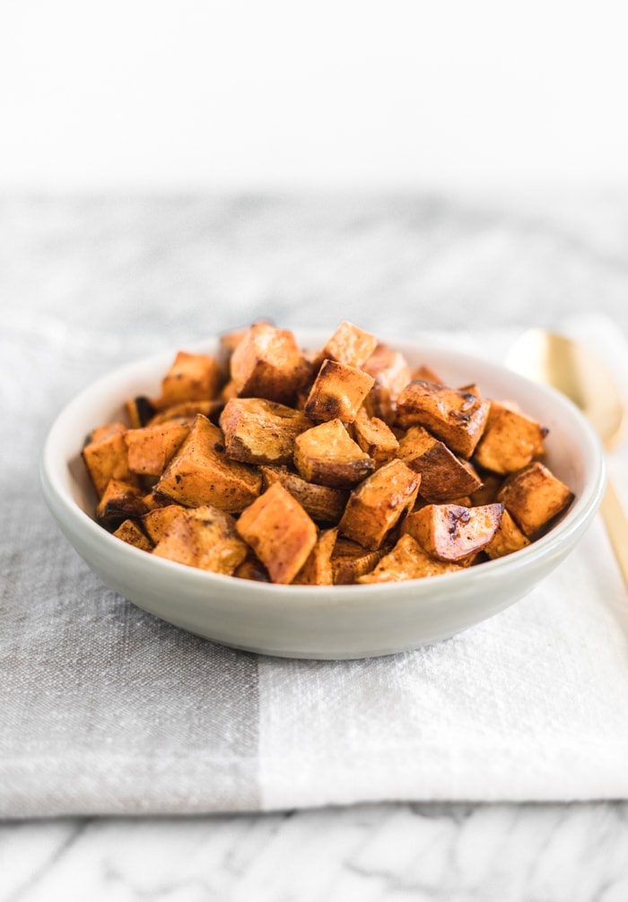 simple roasted sweet potato cubes in a grey bowl on top of a folded grey and white napkin.