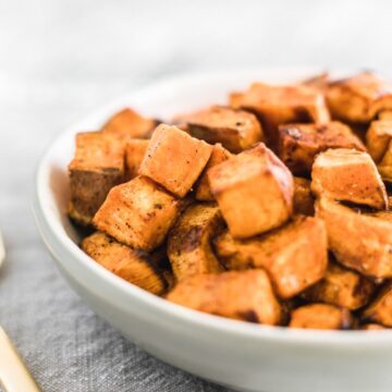 closeup of simple roasted sweet potato cubes in a white bowl.