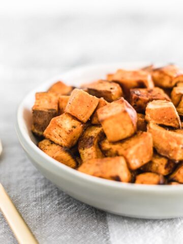 closeup of simple roasted sweet potato cubes in a white bowl.
