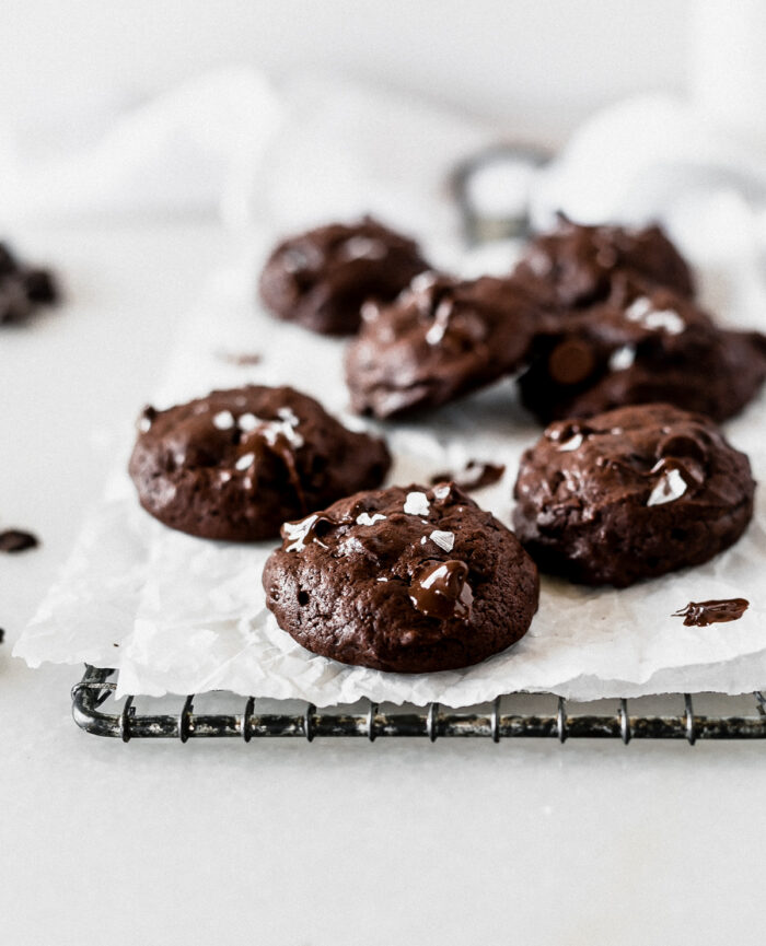 Triple chocolate cookies with flake salt on top on a cooling rack lined with parchment.