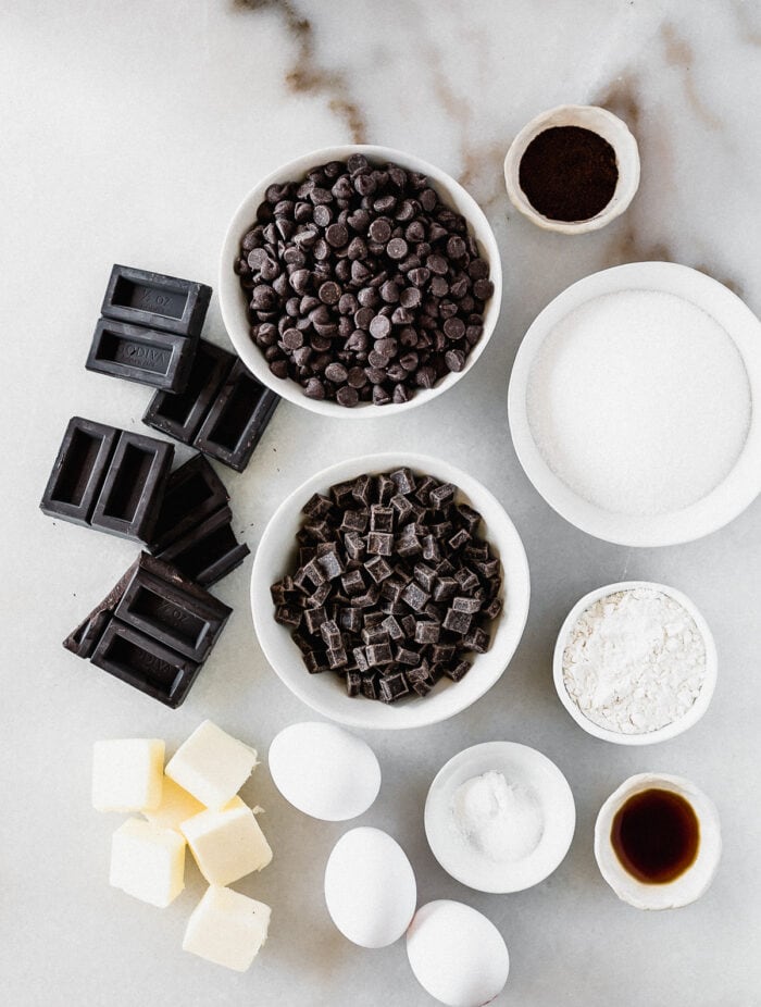 overhead view of ingredients needed to make triple chocolate brownie cookies on a white marble background.