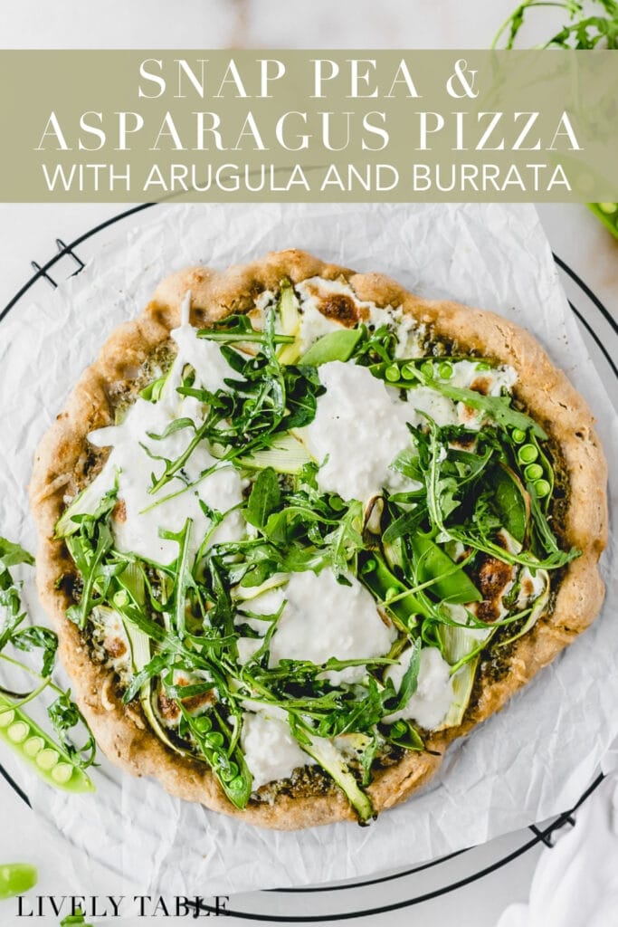 overhead view of asparagus snap pea pizza with burrata and arugula on a wire cooling rack lined with parchment with text overlay.