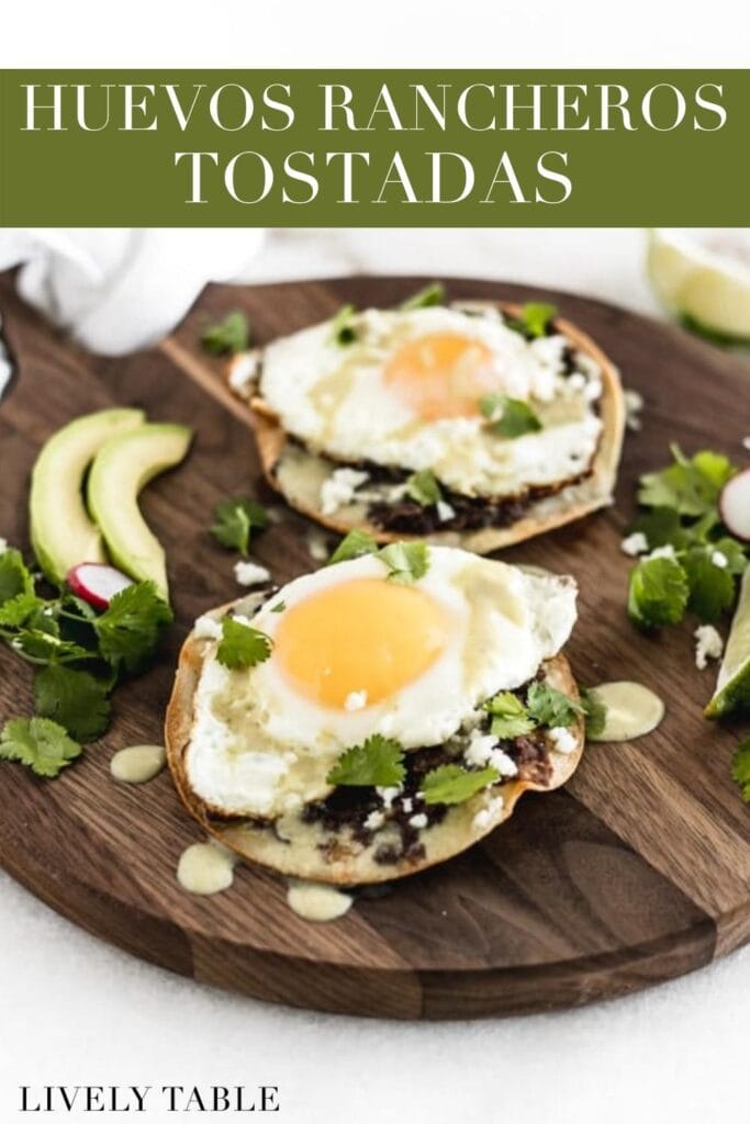 two huevos rancheros tostadas on a round serving board with text overlay.