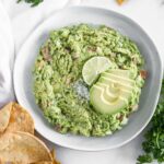 easy homemade guacamole in a bowl with chips around it.
