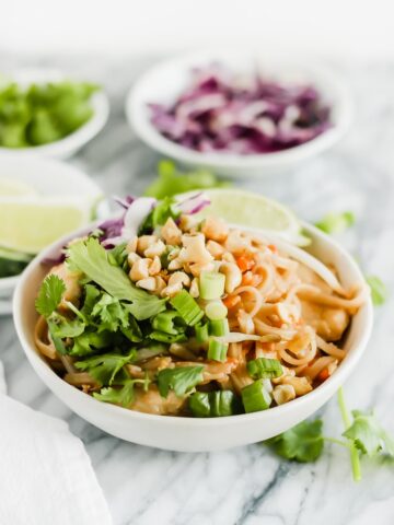 closeup of healthy chicken pad thai in a white bowl.