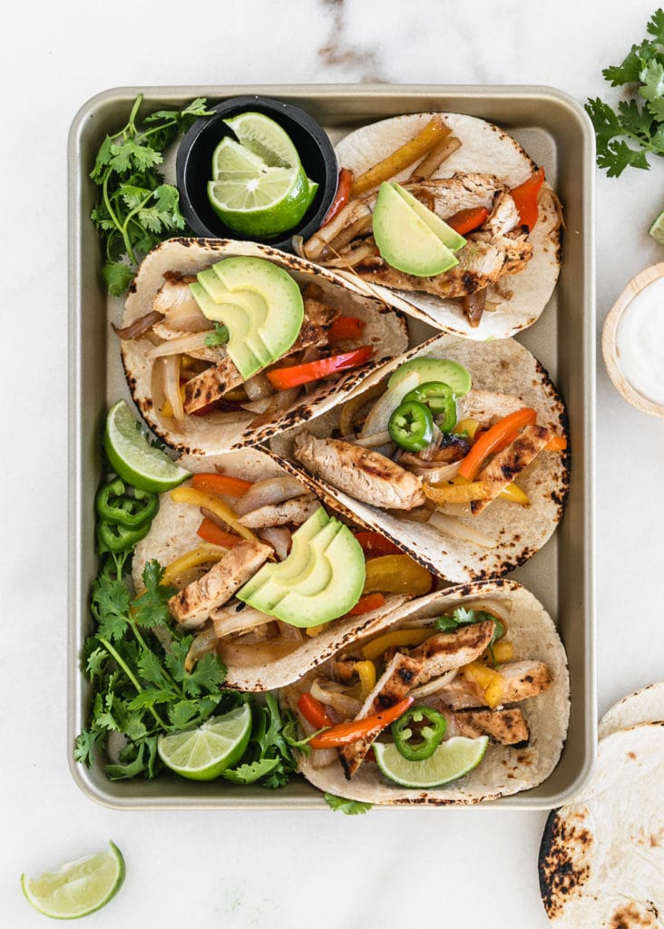 grilled chicken fajita tacos on a pan with bell peppers and avocado.