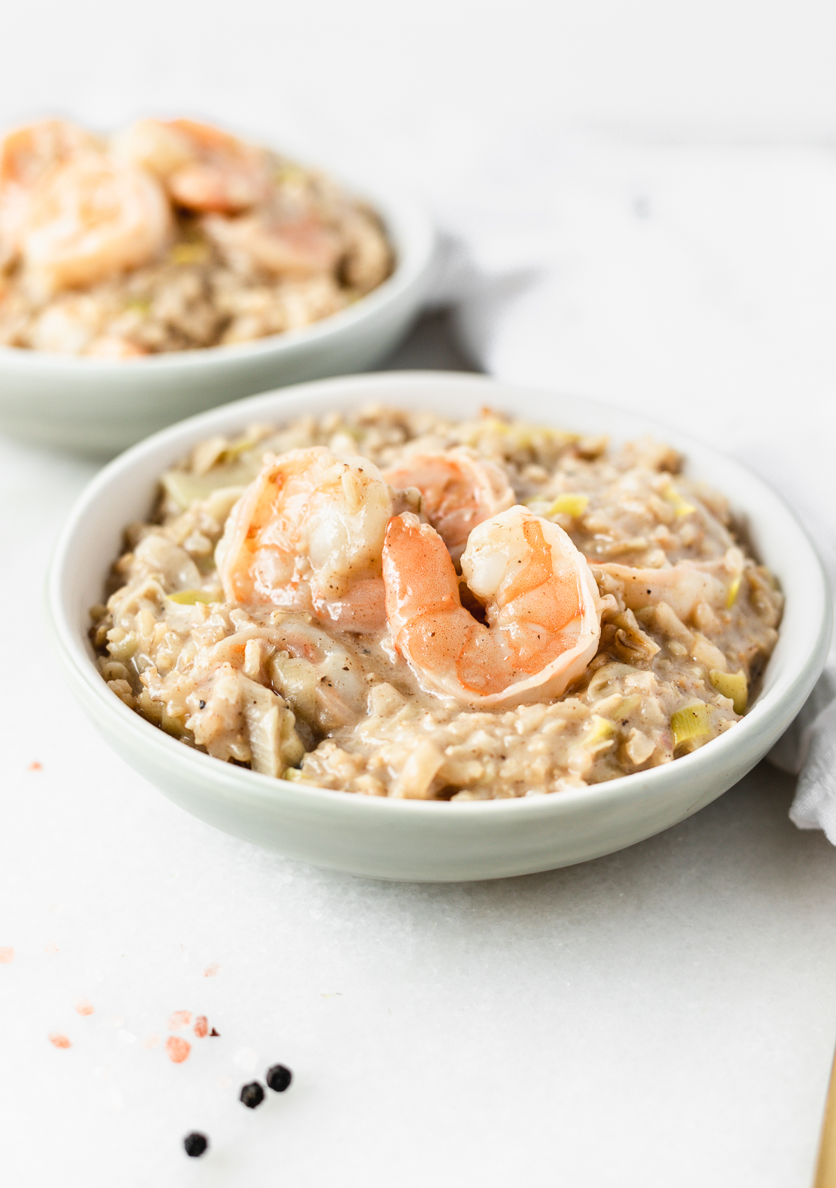 closeup of brown rice shrimp and leek risotto in a grey bowl.