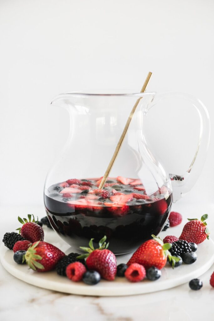 Antioxidant red berry Sangria in a pitcher on a tray with berries.