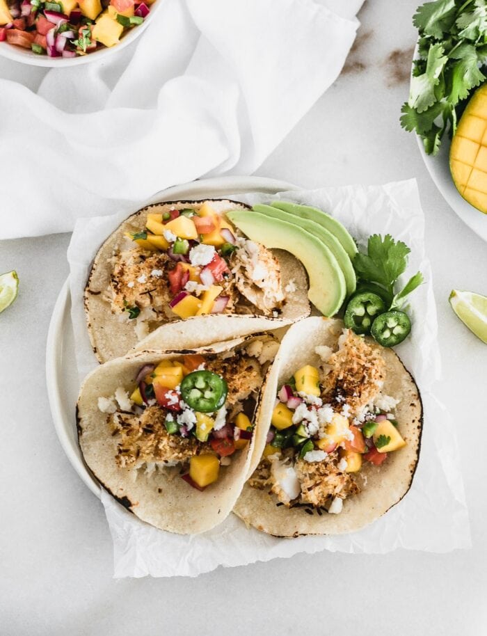 overhead view of crunchy coconut fish tacos topped with a fresh mango salsa.