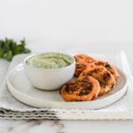 Roasted poblano sweet potato cakes on a plate with a green sauce.