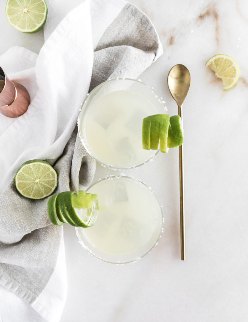 Top view of two skinny margaritas with lime wedges.