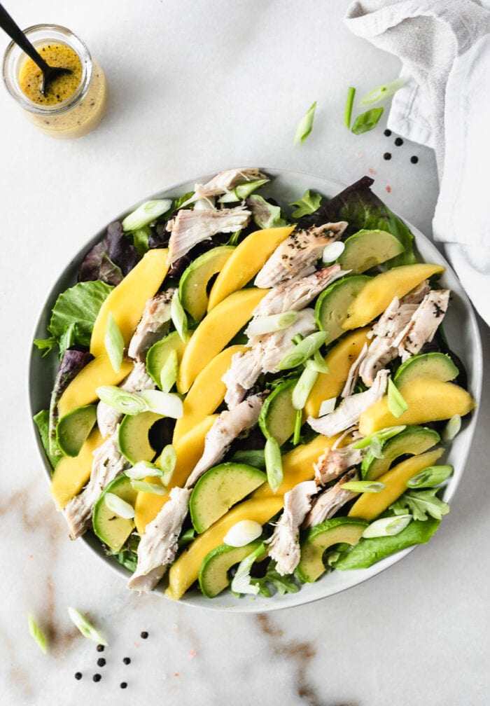 overhead view of roasted chicken mango avocado salad on a grey plate.