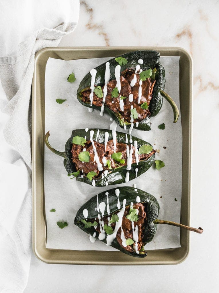 Mole chicken stuffed poblanos on a cooking sheet.