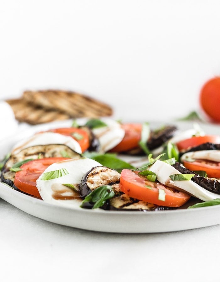 grilled eggplant layered with sliced tomatoes and mozarella with basil and balsamic vinegar on a plate