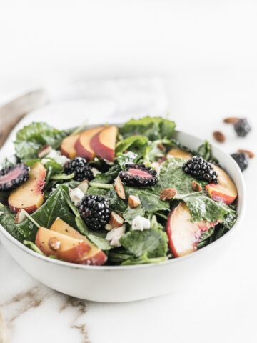 blackberry peach kale salad in a white bowl.