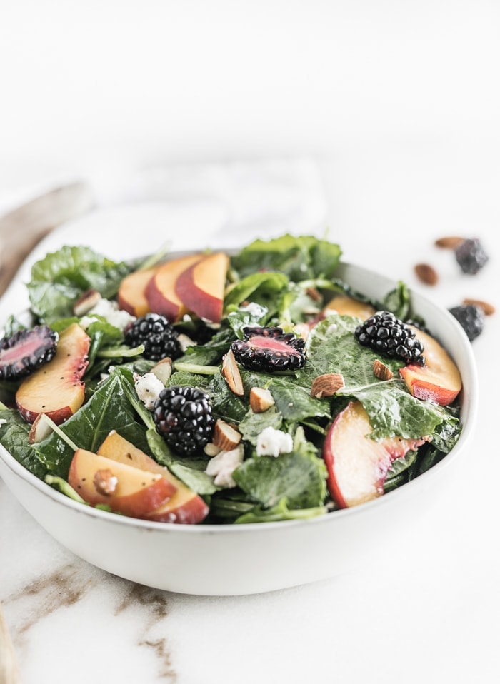 This delicious Blackberry Peach Kale Salad is a great way to eat summer fruit! With toasted almonds, goat cheese, mint and a lemon poppy seed vinaigrette, it's a perfect light lunch or side dish! (#glutenfree, #vegetarian) | #kalesalad #summersalad | via livelytable.com