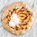 overhead view of peach galette with ice cream on top on a marble backdrop