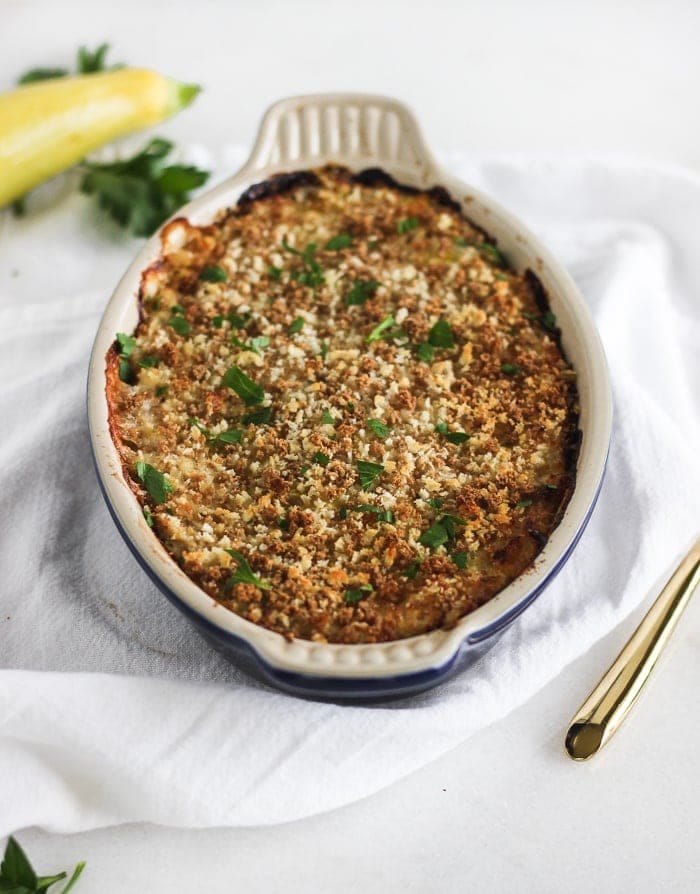 cheesy summer squash casserole with panko topping in a blue oval baking dish