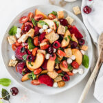 overhead view of stone fruit panzanella salad on a grey plate.