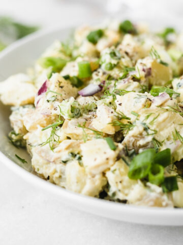 closeup of healthy dill potato salad in a white bowl.