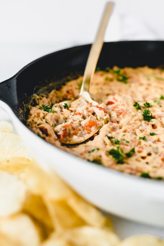closeup of a gold spoon in a skillet of hot crab dip.