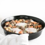 apple sweet potato hash in a black skillet with a white napkin.