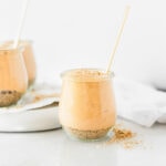 healthy no bake pumpkin cheesecake in a glass jar with a gold spoon in it.