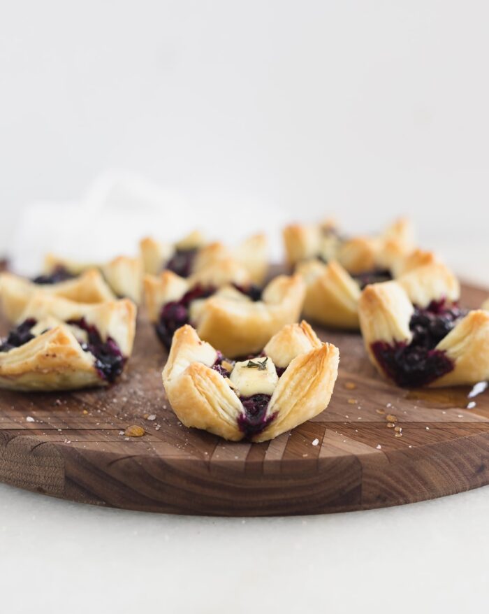 Easy blueberry brie puff pastry bites on a wooden serving tray.